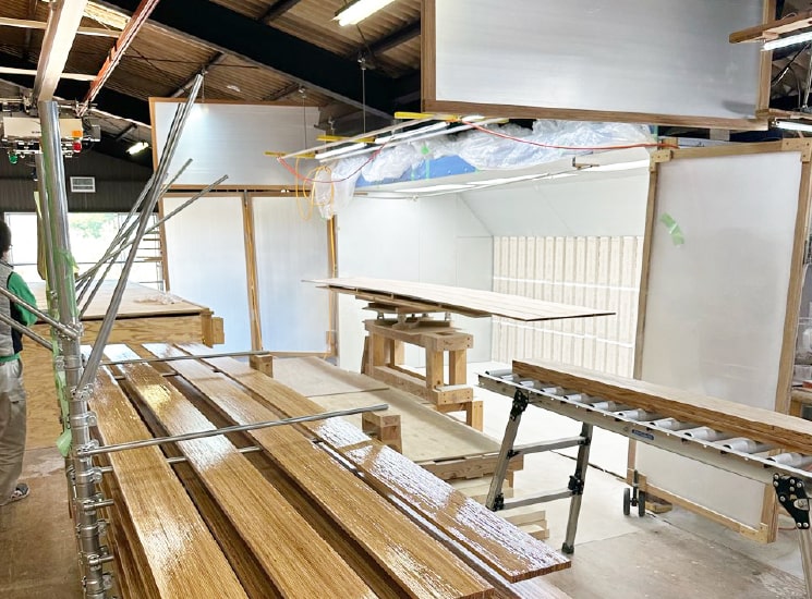 塗装作業の様子 塗装ブースの前に木材や木材を流すレーンを並べ、効率的に作業している