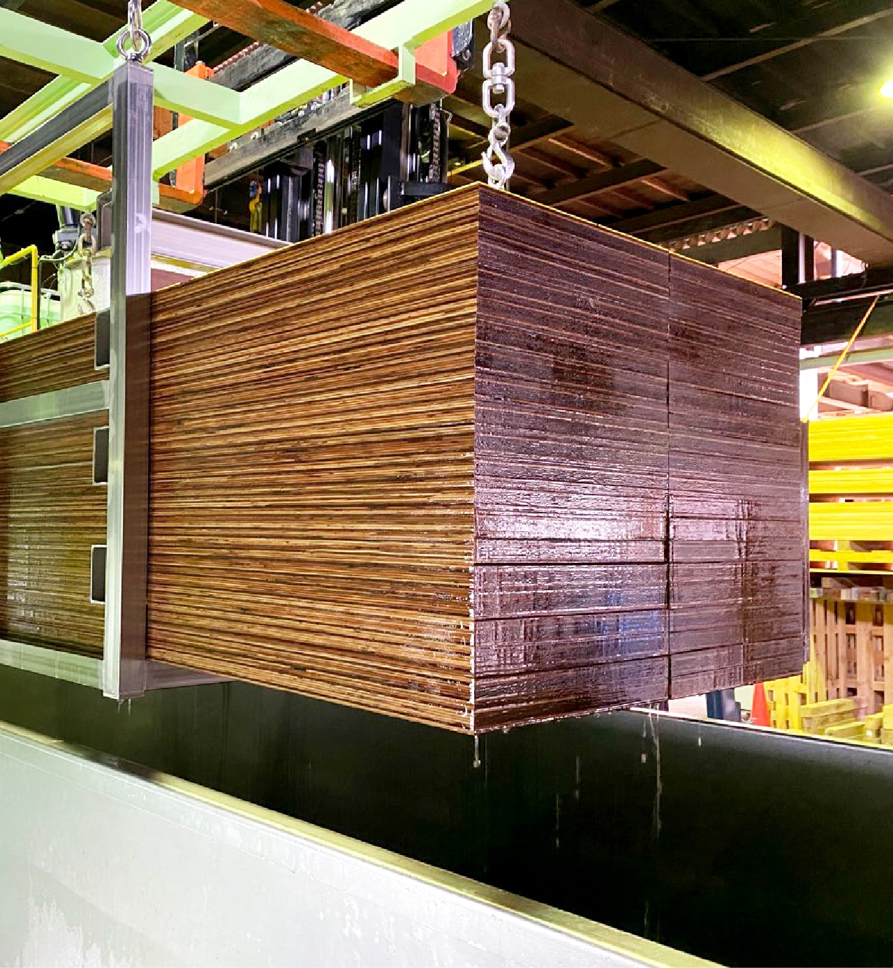 不燃木材製造の様子 金属製のバットから、薬液を含浸した木材をフォークリフトにより取り出している